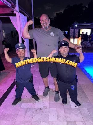 Little people performers dressed as police officer characters posing with a guest at a Miami poolside event